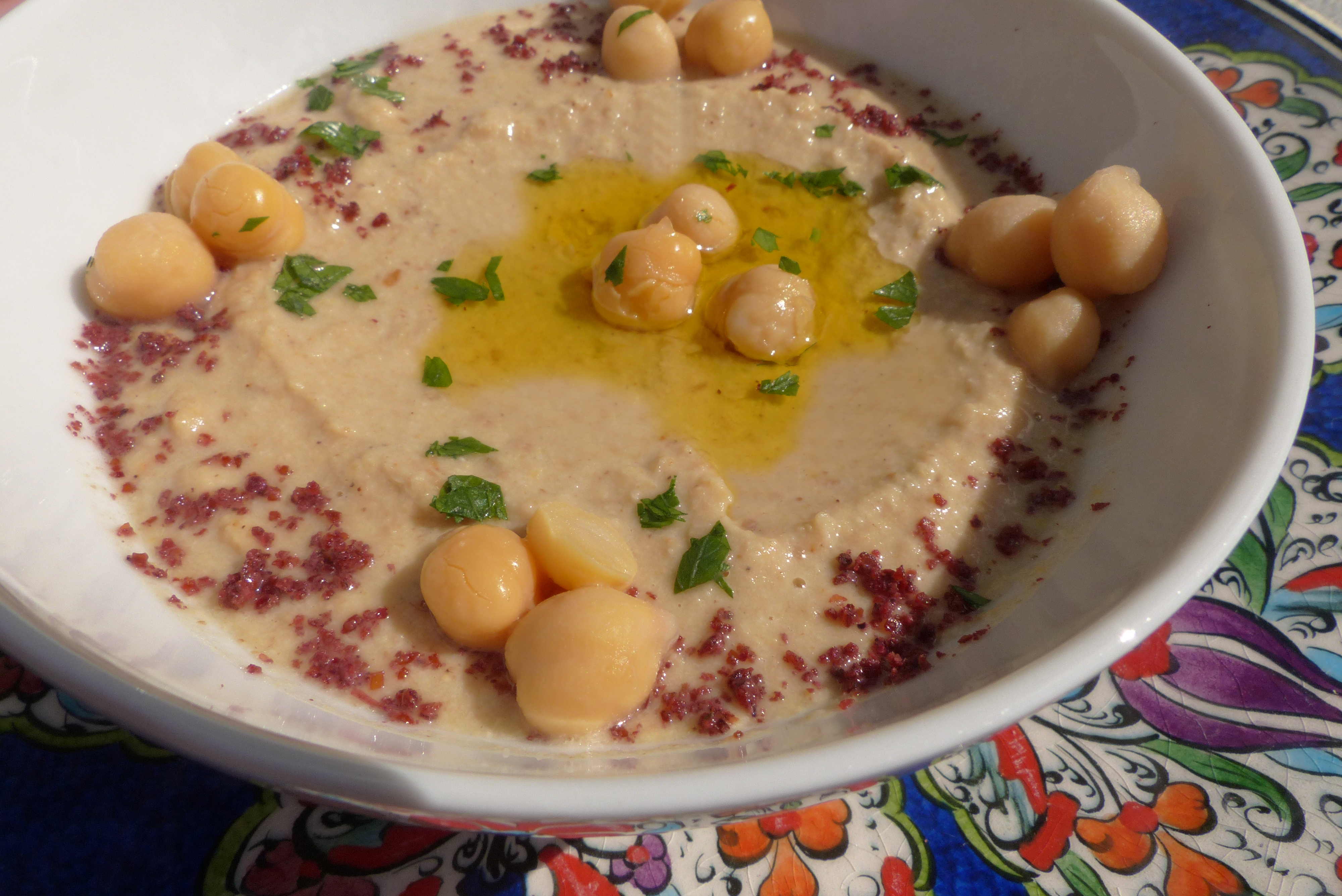 <p>Traditioneller Hummus mit einem Topping aus Sumach, Petersilie, Olivenöl und einigen Kichererbsen.</p>