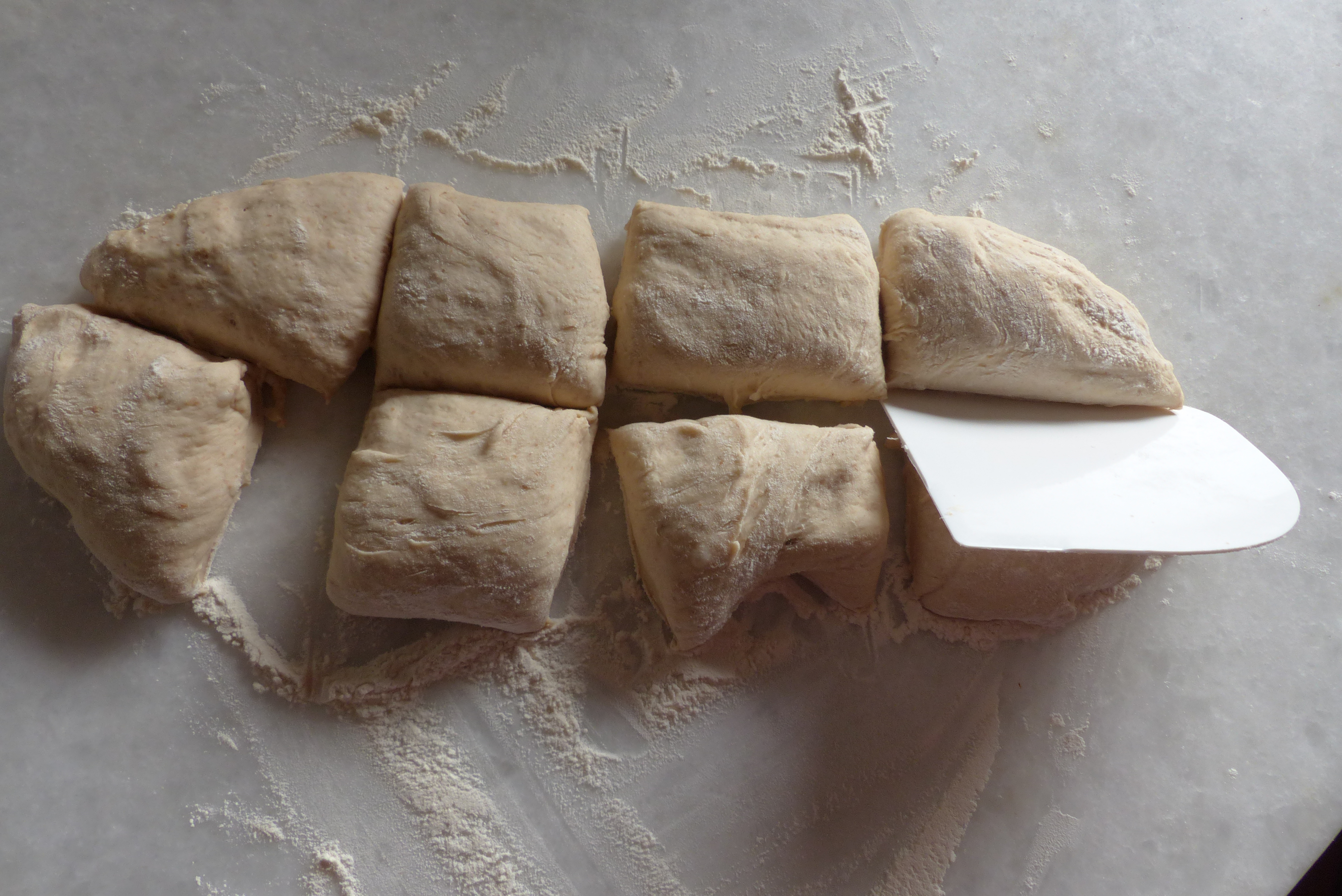 <p>Die Teigplatte in acht ca. 10 cm große Teigstücke schneiden.</p>