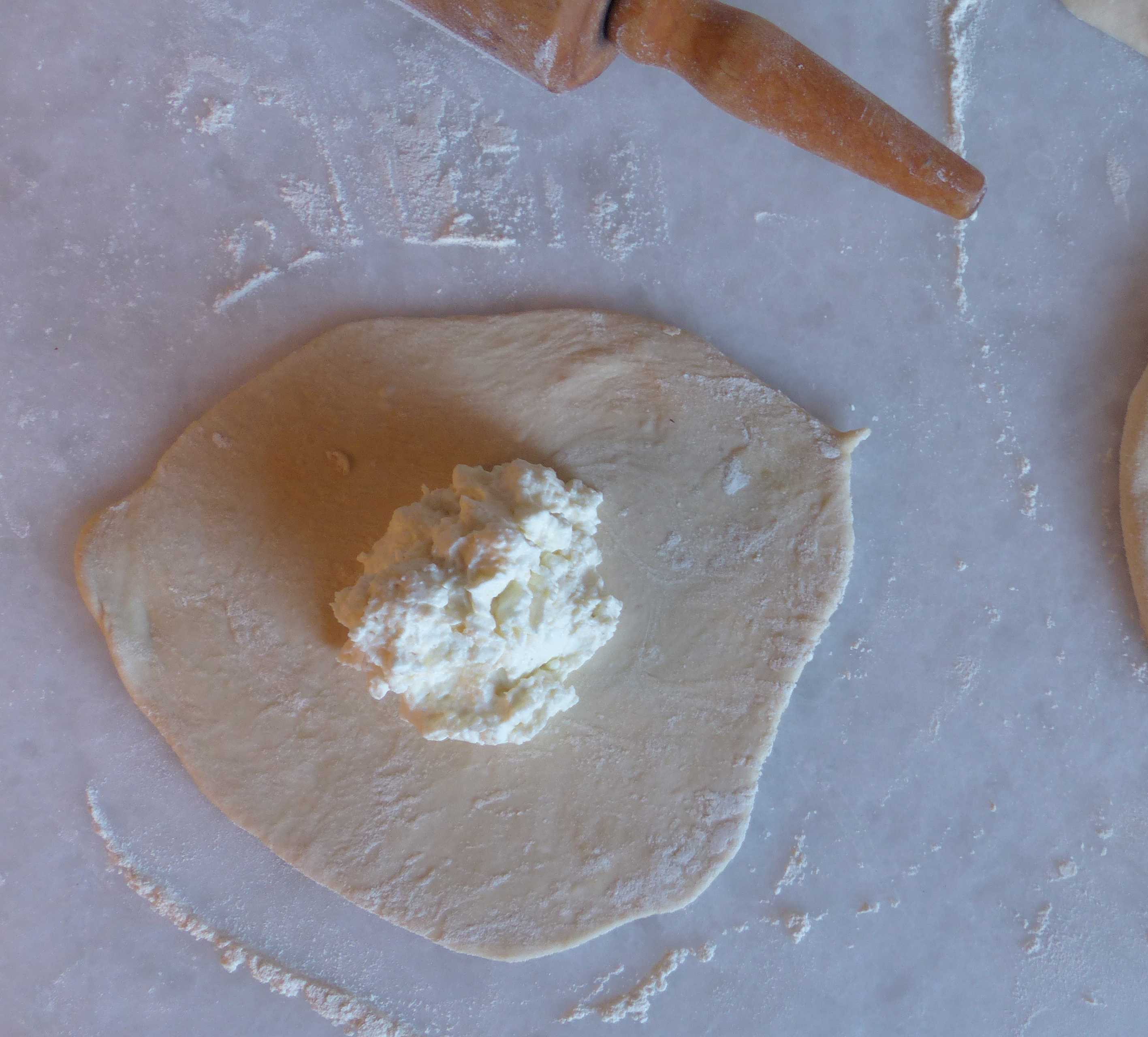 <p>Dünner Teigfladen mit mittig gesetztem Weichkäse</p>