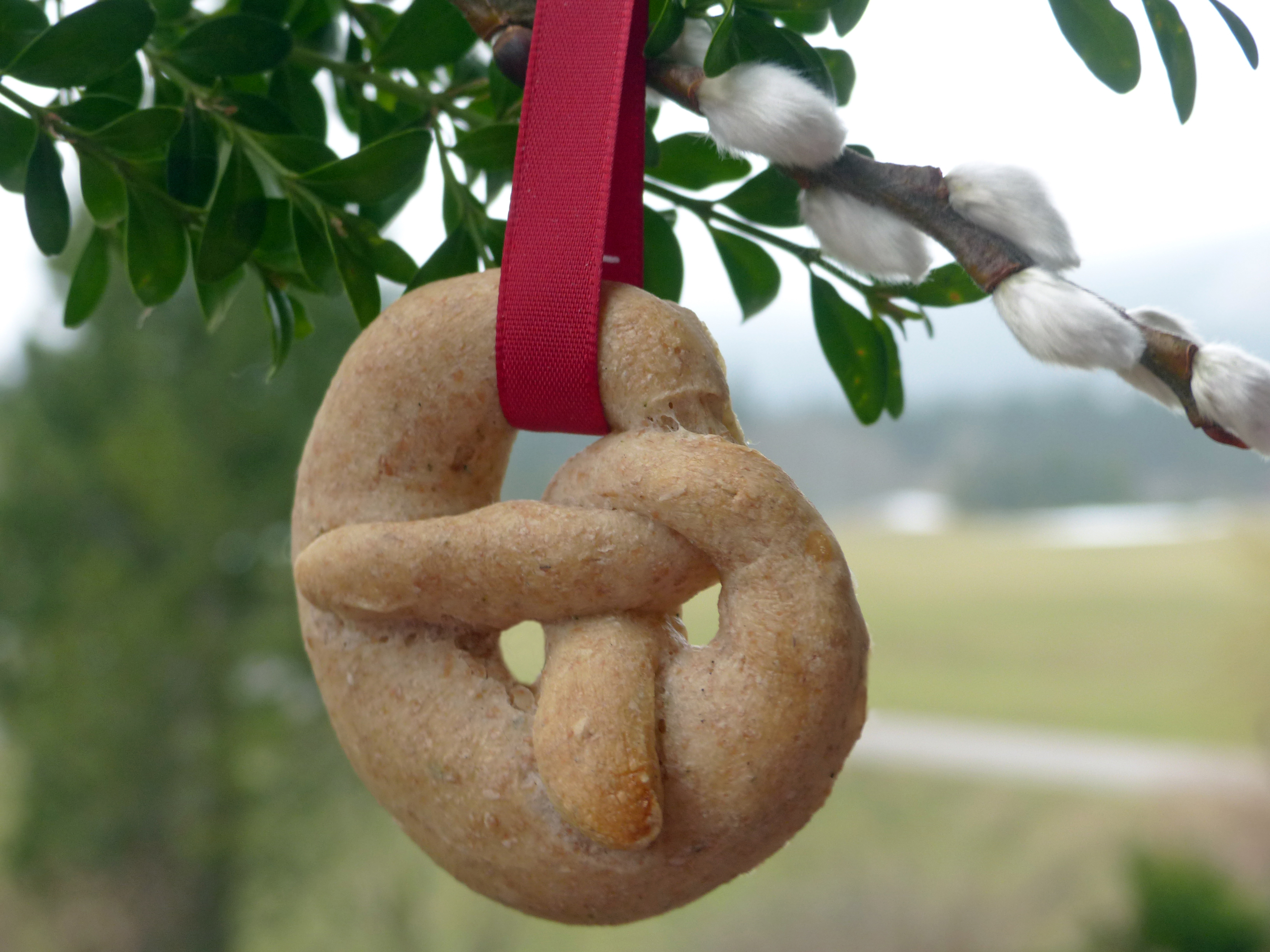 <p>Im christlichen Sinn ist die Breze (Brezenschlange ;) als Gebildbrot Symbol für den zyklischen und fortdauernden Charakter des Lebens, ermöglicht und begleitet durch den dreieinigen Gott. Er scheint als Sonne durch alle drei Fenster, die eine Einheit bilden, und begleitet Geburt, Leben auf dieser Welt und Tod  -  oder: Vergangenheit, Gegenwart, Zukunft.</p>