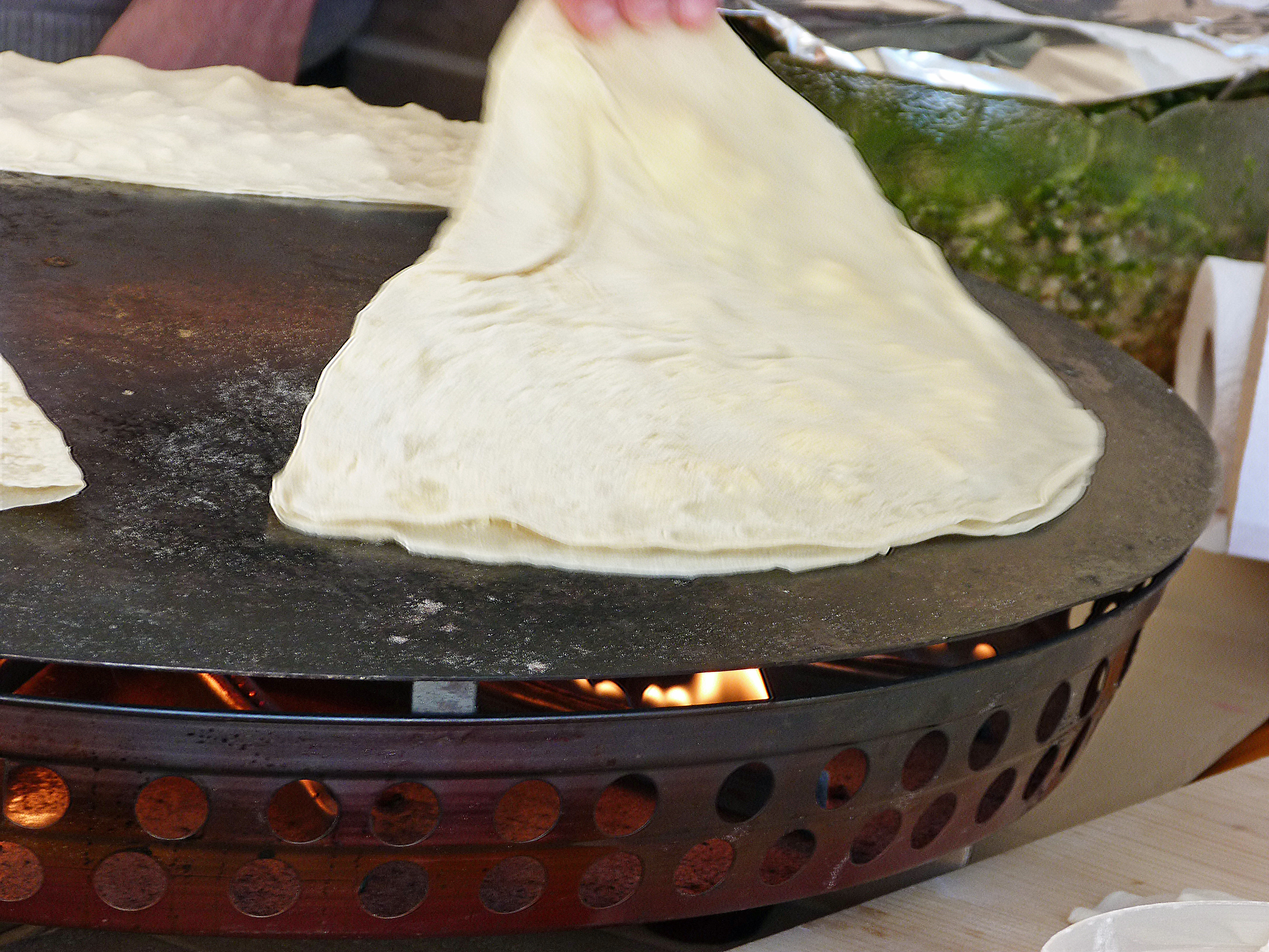 <p>Mit Schwung wird die Teigtasche auf den heißen sac - wie auf dem Foto - oder auf eine heiße Grillplatte bzw. in die Pfanne befördert. </p>
