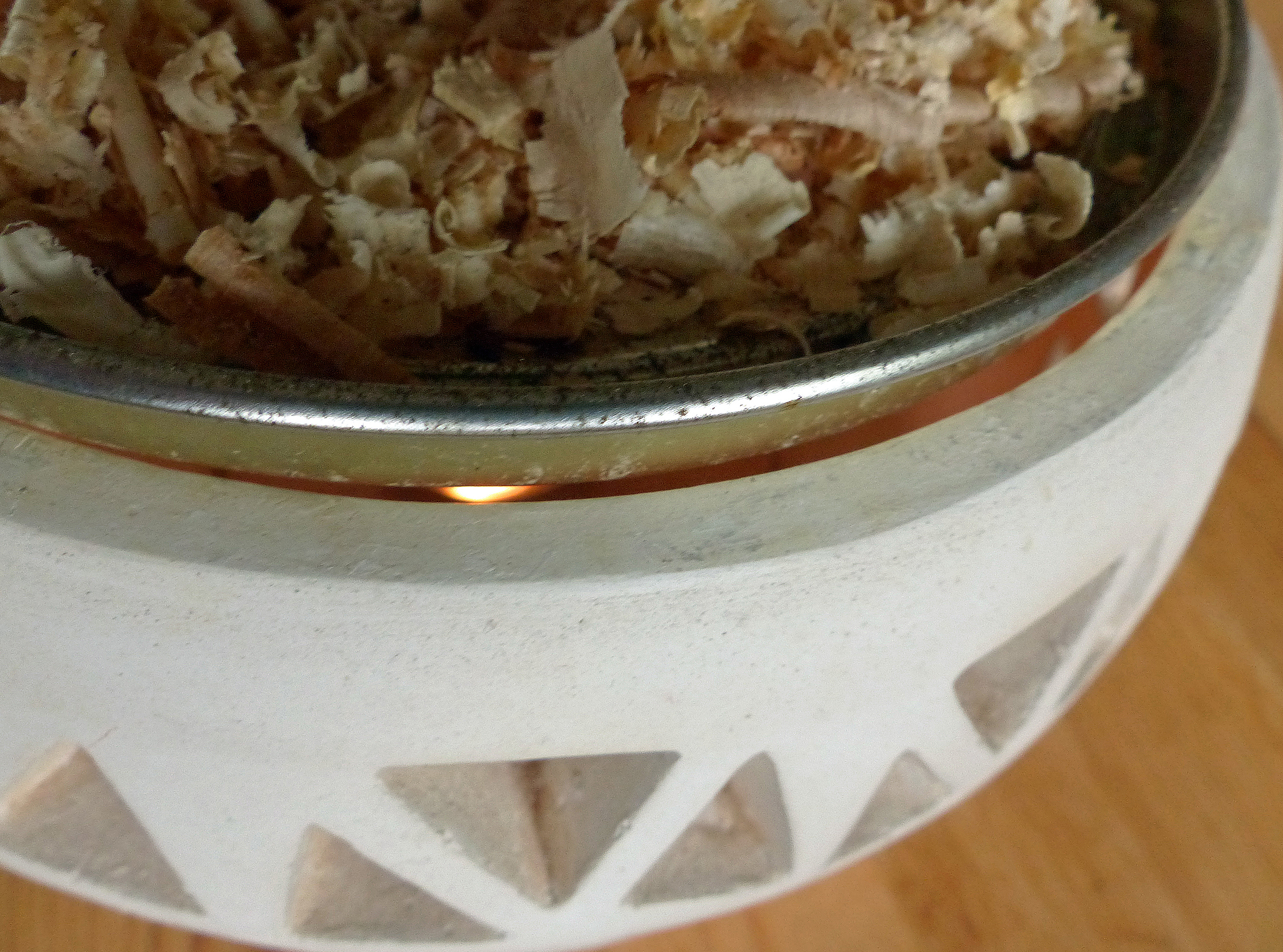 <p>Räucherwerk, im Foto Zirbenspäne, lässt sich auf einem Metallteller eines Räucherstövchens verräuchern. Legt man Harz dazu, wird es nach dem Räuchern mit Öl gereinigt.</p>