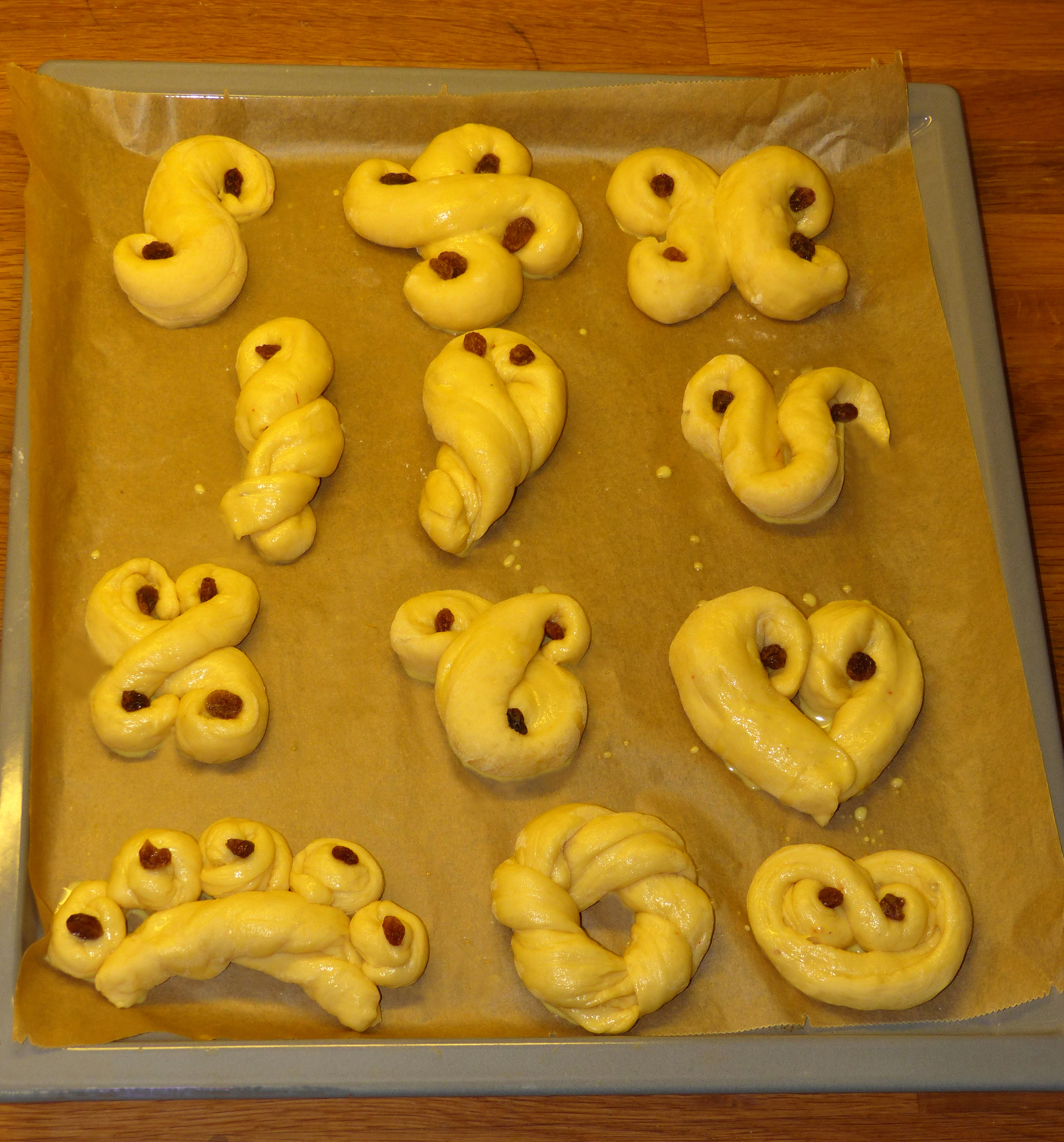 <p>Lussebollar vor dem Backen. Sie sind bereits eingepinselt. Man erkennt in diesem Zustand ihre Formgebung besonders gut!</p>