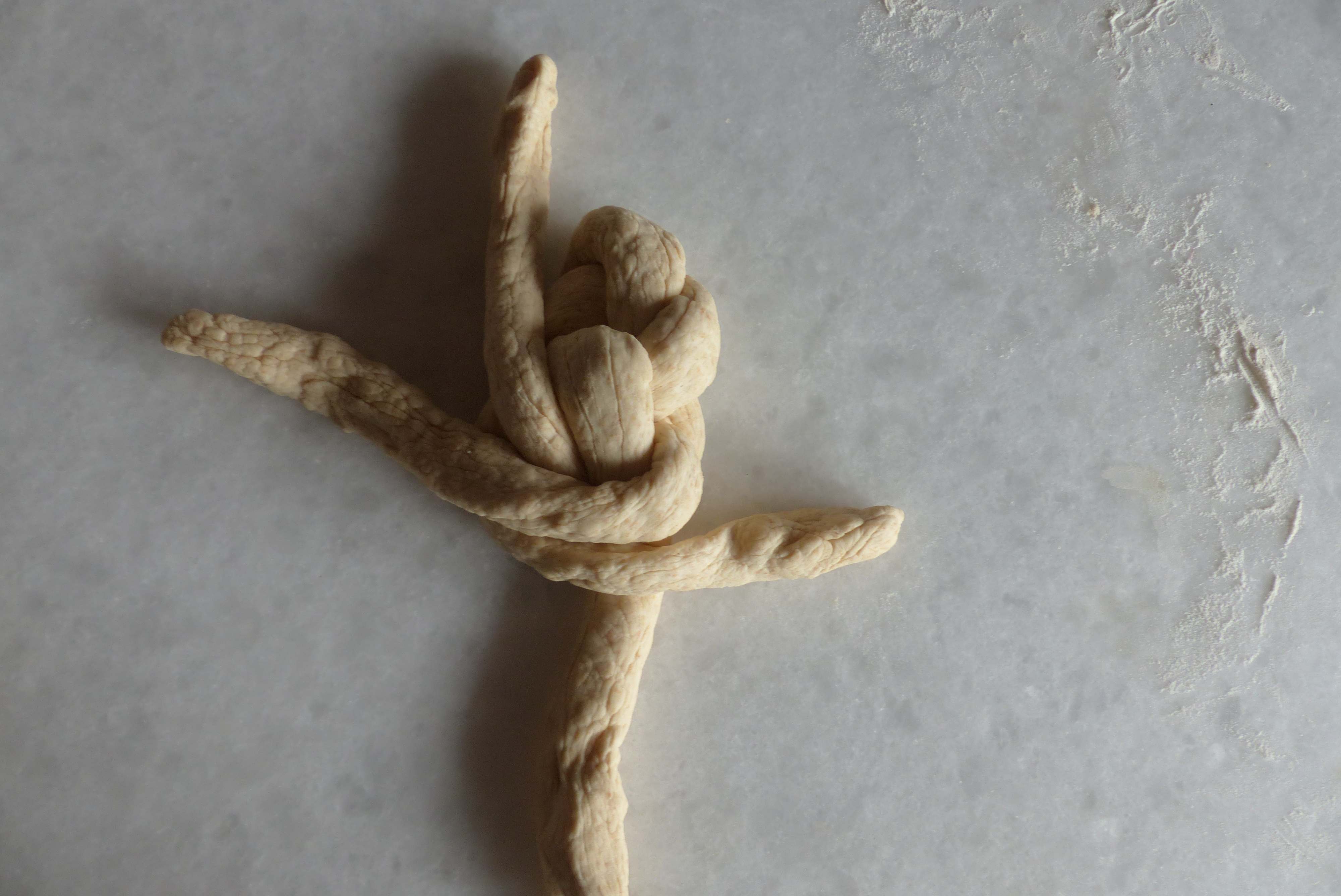 <p>Die linke Stranghälfte wird <strong>unterhalb des Mittelpunkts</strong> waagrecht nach rechts gezogen, wo man sie ablegt.</p>