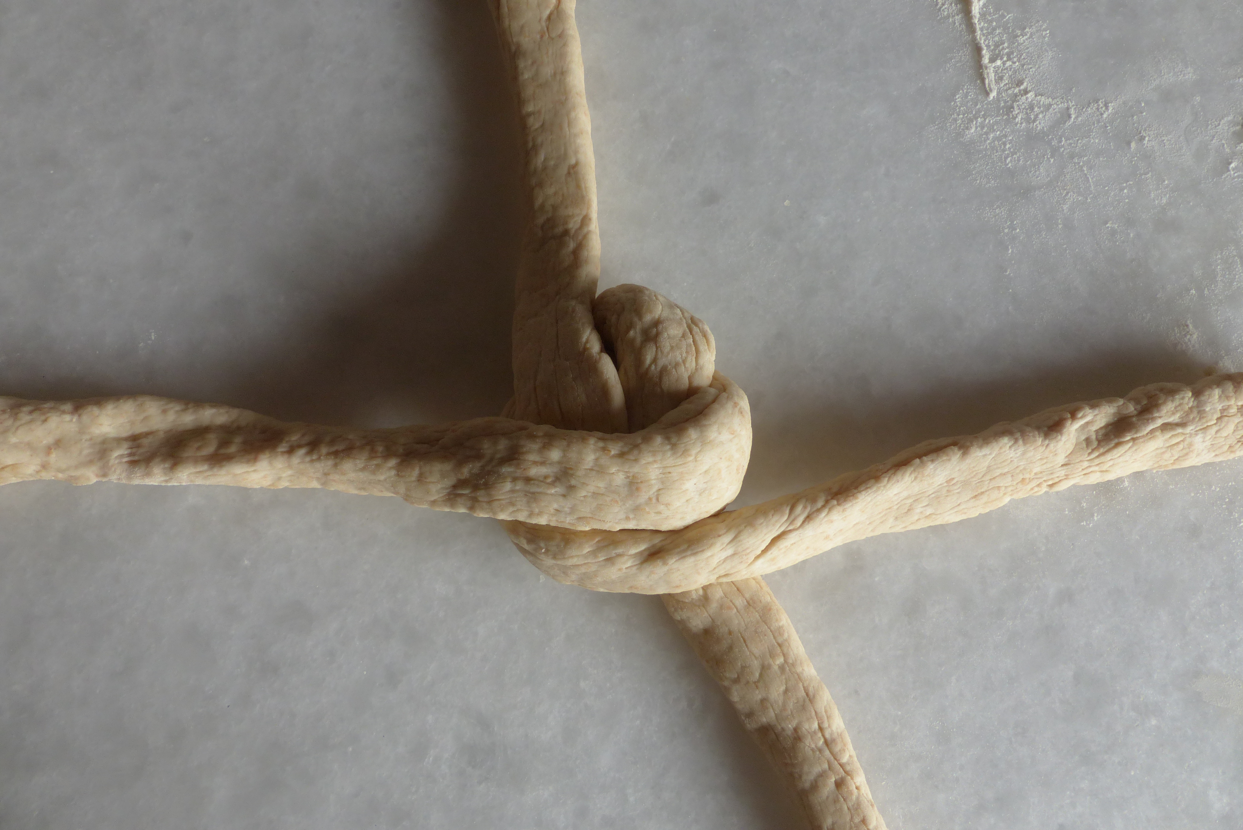 <p>Die linke Stranghälfte wird <strong>unterhalb des Mittelpunkts</strong> waagrecht nach rechts gezogen, wo man sie ablegt.</p>